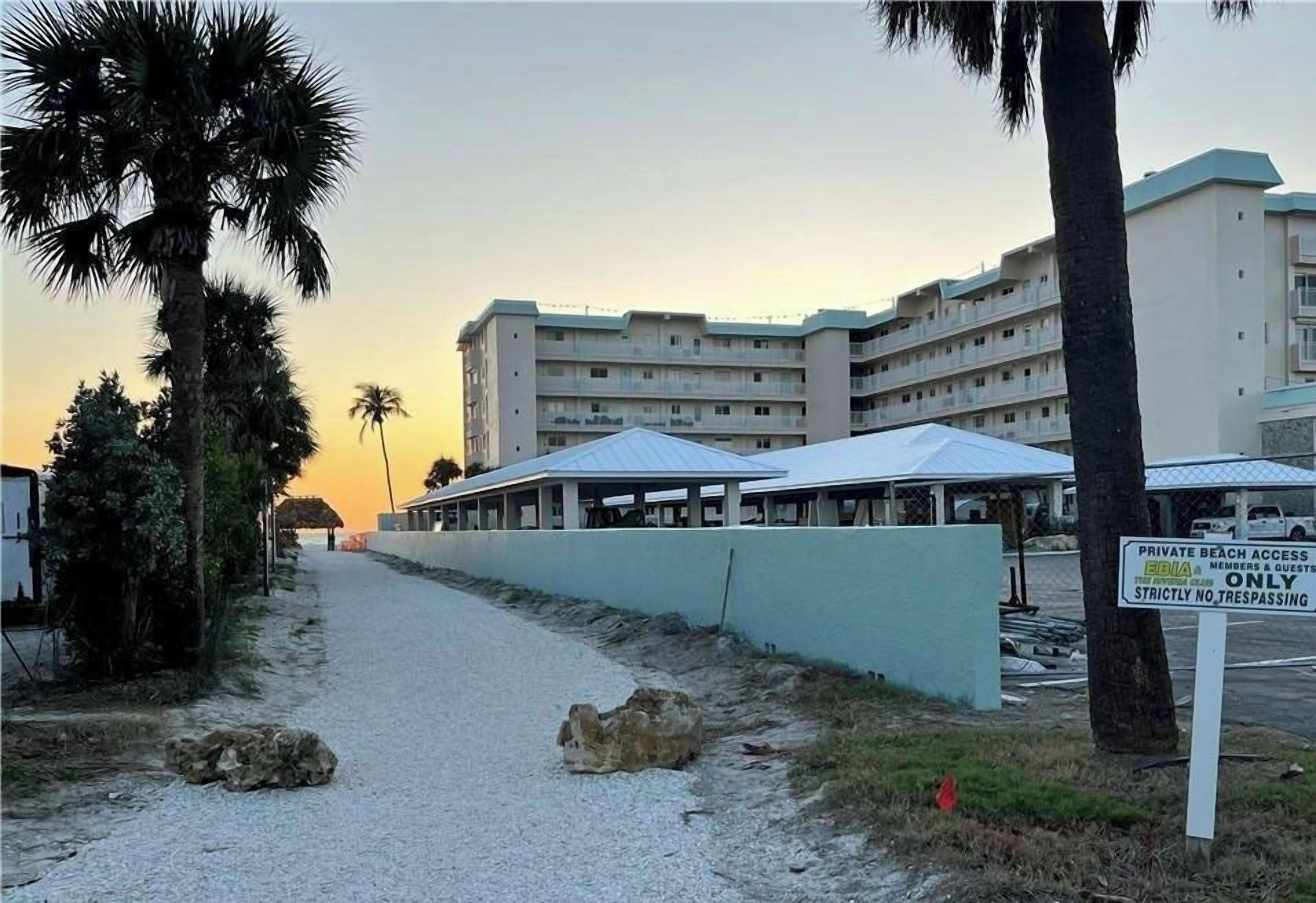 A hotel with multiple floors, a covered outdoor area, and a private beach access sign.