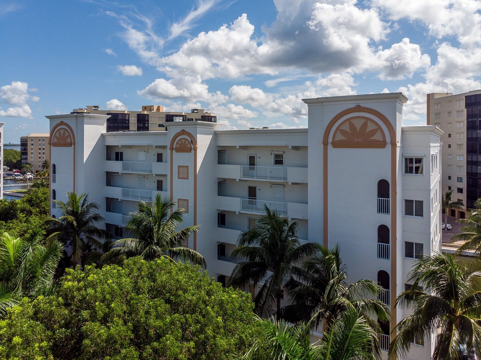 A multi-story hotel with balconies, palm trees, and a clear sky.