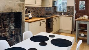 Une cuisine moderne avec des meubles blancs, un plan de travail noir et un lustre.