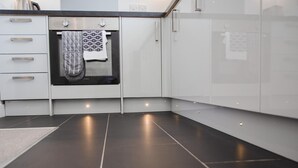 A modern kitchen with white cabinets, a black oven, and a patterned towel hanging on the oven door.