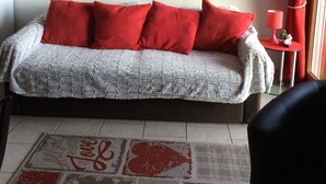 A cozy living room with a grey sofa, red cushions, a mirror, and a small table with a red lamp. - Apartment with lake view in residence (Gérardmer)