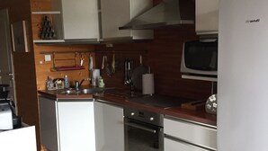 A modern kitchen with white cabinets, a stainless steel oven, a microwave, and a refrigerator. - Apartment with lake view in residence (Gérardmer)