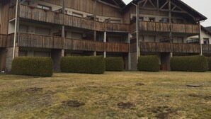 A multi-story wooden building with balconies, a stone base, and a grassy courtyard. - Apartment with lake view in residence (Gérardmer)