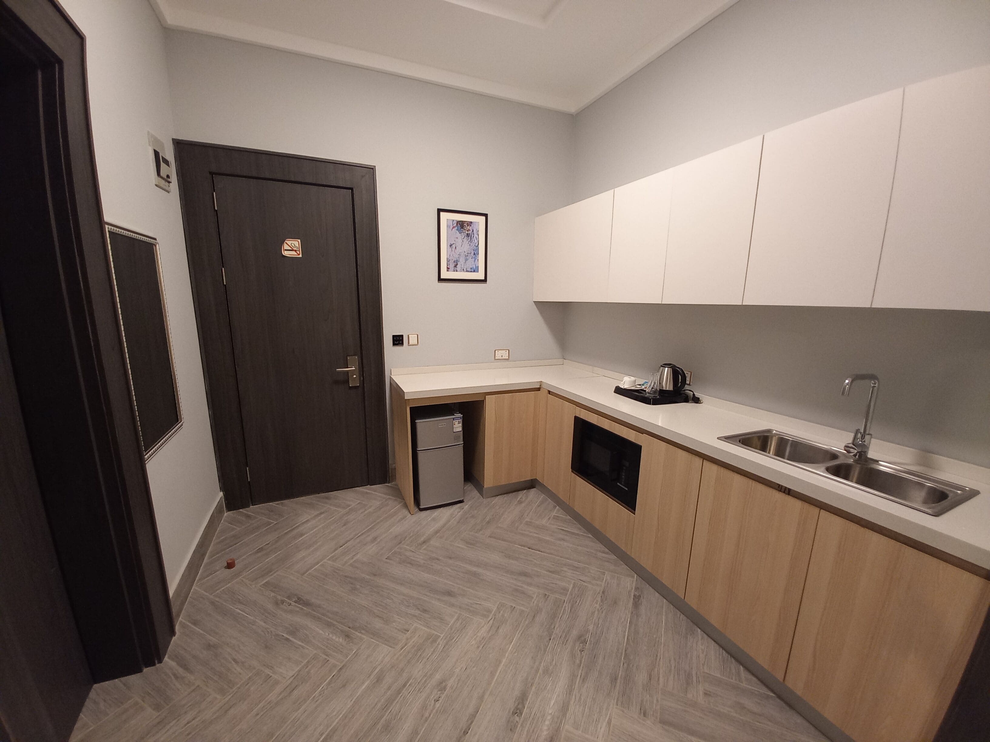Una cocina moderna con armarios de madera, un lavamanos de acero inoxidable y un refrigerador pequeño.