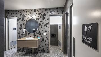 Un baño moderno para hombres con un revestimiento de pared con diseño de granito, un lavamanos y un letrero que indica las instalaciones.