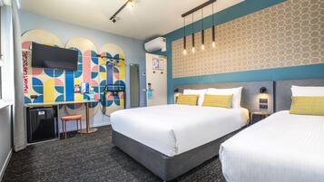 A hotel room with two beds, a desk, and a TV.