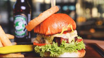 Una hamburguesa con papas fritas y una botella de cerveza en una bandeja.