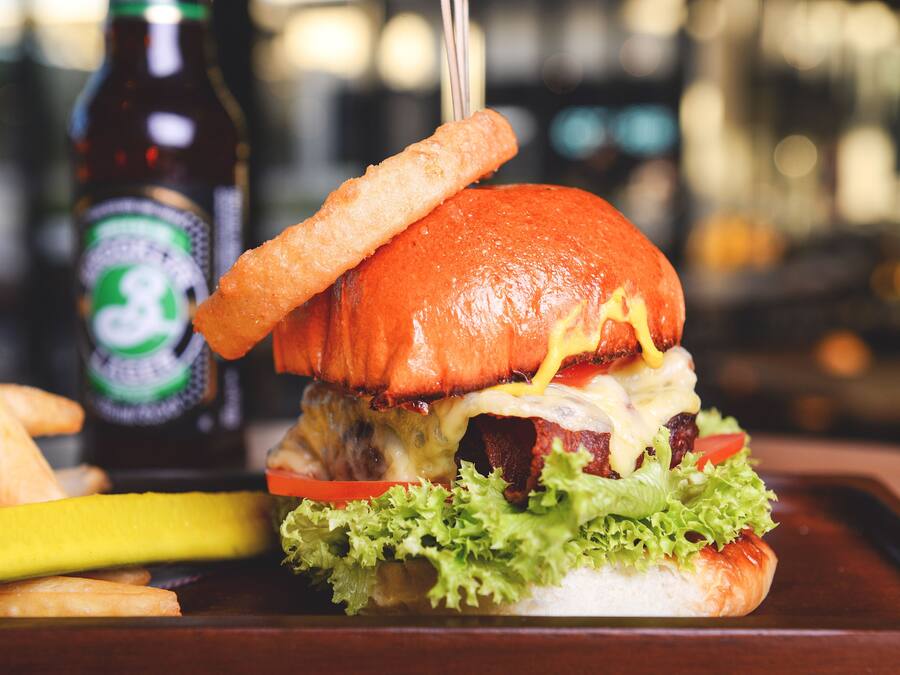 Una hamburguesa con papas fritas y una botella de cerveza en una bandeja.
