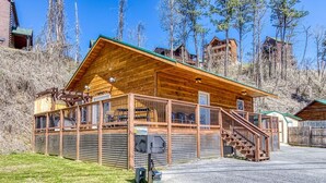 Une cabane en bois dotée d’une véranda, d’un escalier et d’une zone délimitée par une clôture.