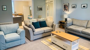A modern living room with two sofas, a coffee table, and a small side table. - The Garden Flat - An Elegant Georgian Single Level Holiday Home (Charmouth)