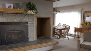 Una sala de estar con chimenea, una mesa de comedor con sillas y un sofá.