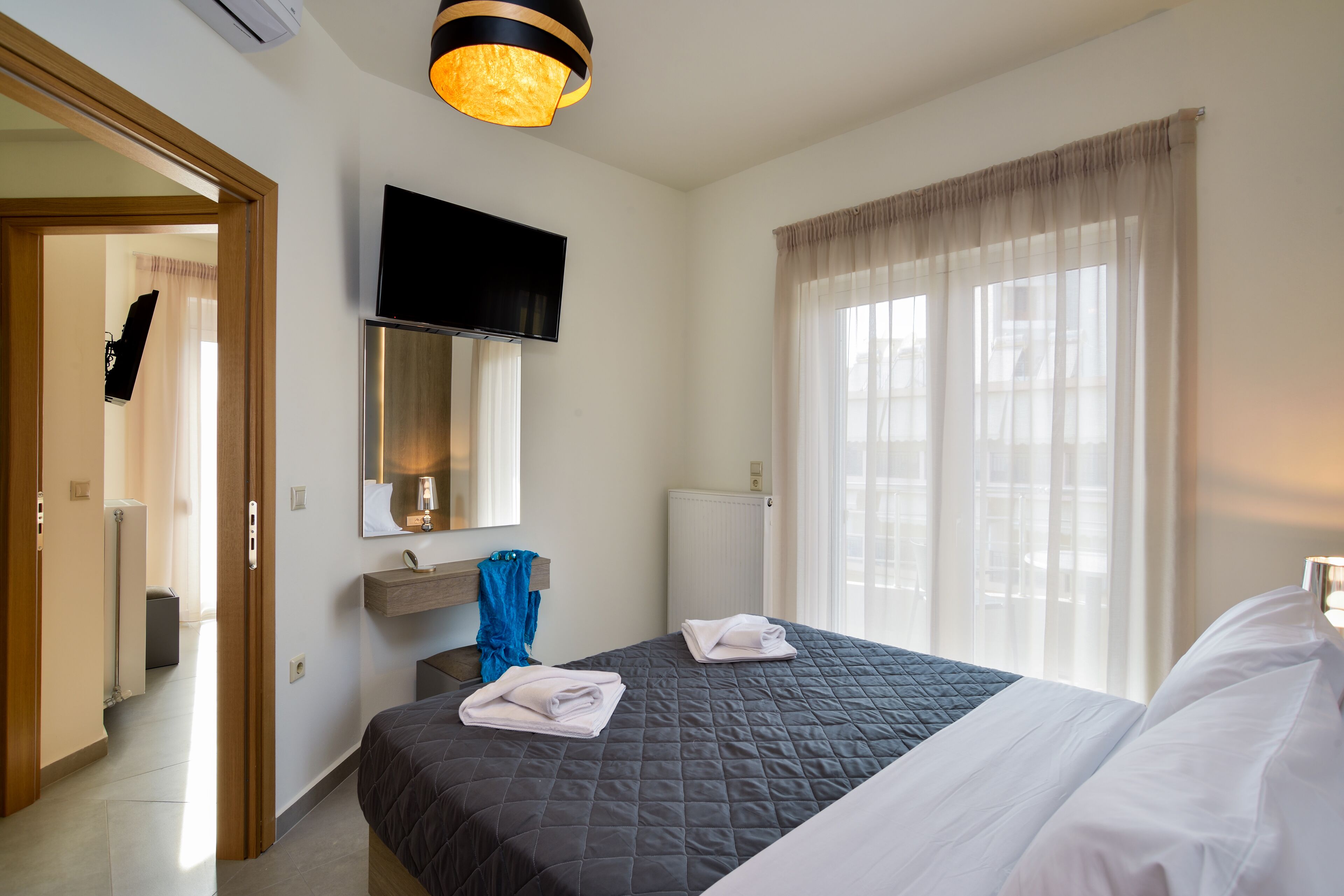 Une chambre d’hôtel avec un lit, un téléviseur fixé au mur, une fenêtre avec des rideaux et un radiateur.