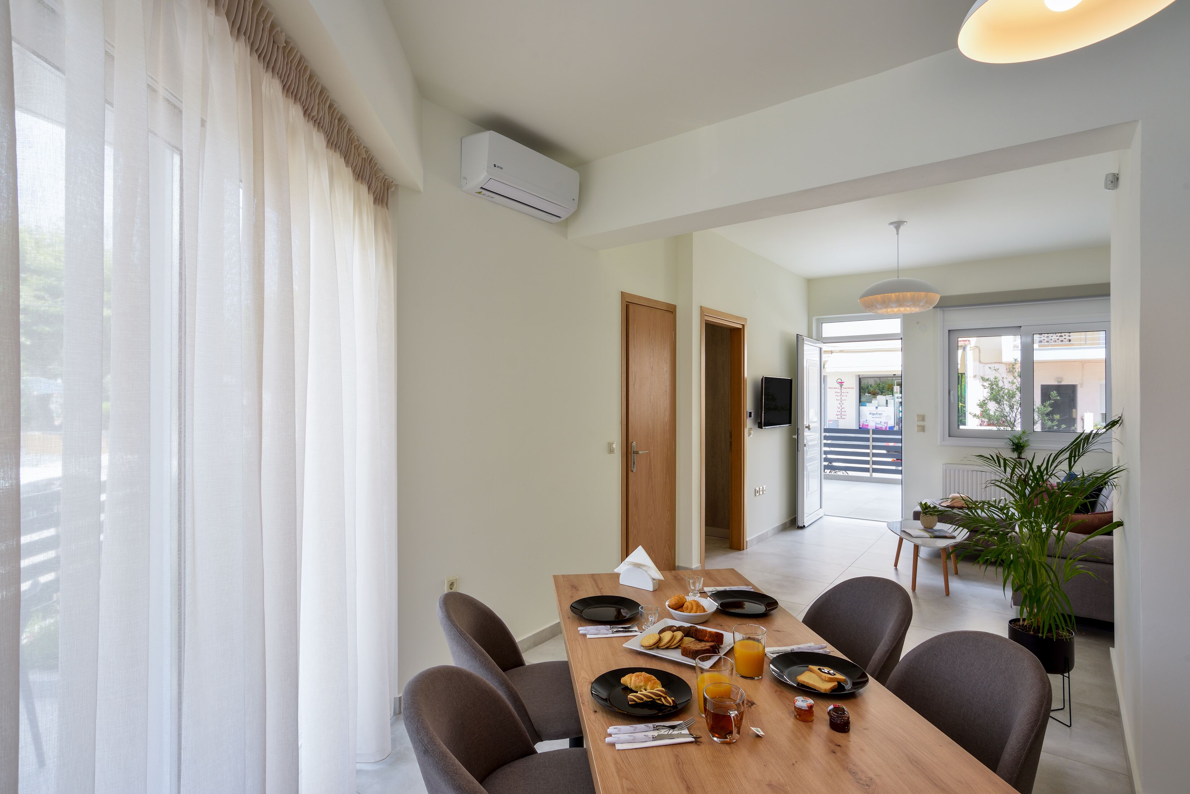 A dining area with a wooden table set for two, a sofa, and a potted plant.