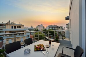A balcony with a table set for a meal, a wine glass, and a bottle of wine.