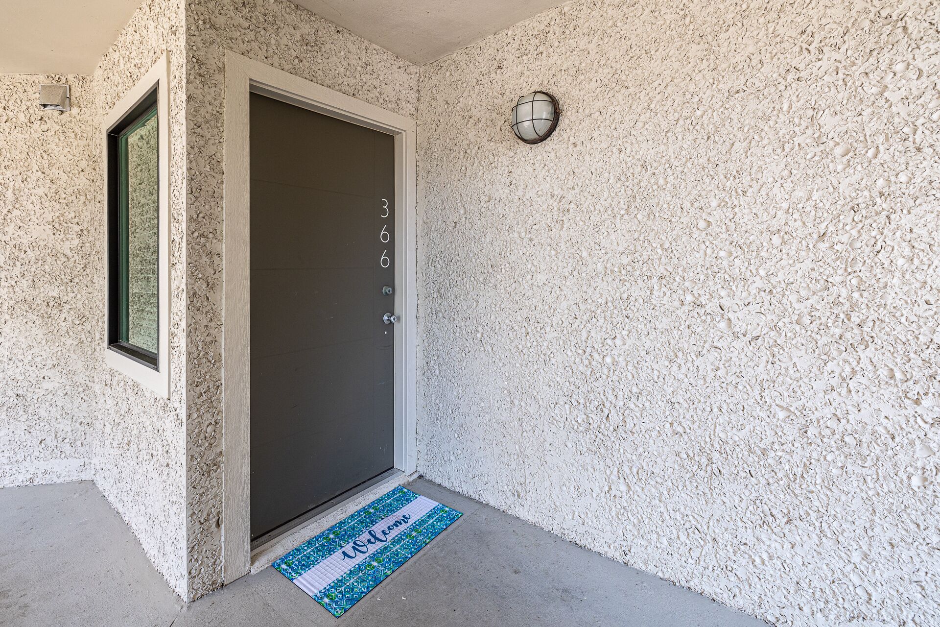 A door with a welcome mat and a textured wall.