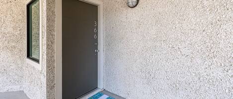 A door with a welcome mat and a textured wall.