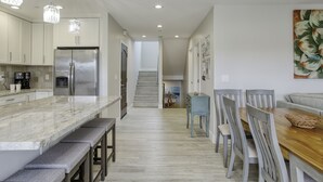 Una cucina moderna con un piano di lavoro in marmo, elettrodomestici in acciaio inossidabile e illuminazione a sospensione.