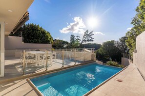 A swimming pool with a glass enclosure, outdoor furniture, and a view of trees and hills. - Sea Views, Pool, Luxurious, Camps Bay - Ravensteyn (Cape Town)