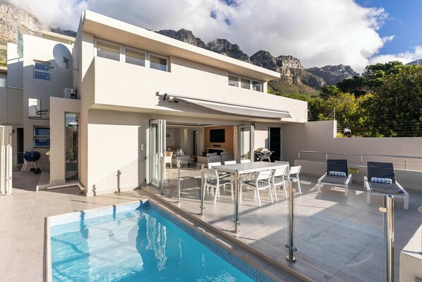 A modern two-story building with a swimming pool, outdoor seating, and mountain views. - Sea Views, Pool, Luxurious, Camps Bay - Ravensteyn (Cape Town)