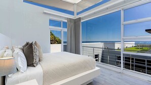 A modern bedroom with a large bed, a nightstand, and a view of the city.