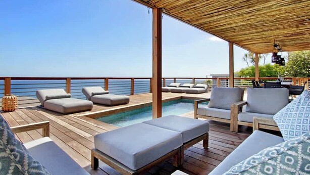 Une terrasse extérieure avec une piscine, des chaises longues et une pergola en bois.