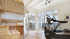 Une salle de sport moderne équipée d’un vélo d’appartement, d’un sauna et de grandes fenêtres.