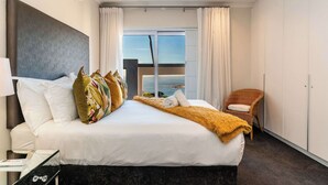 Une chambre d’hôtel avec un grand lit, une vue sur la mer, une chaise et une armoire.