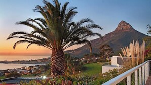 A coastal landscape with a prominent palm tree, a mountain in the background, and a view of a town across the water. - Ocean Views, Pool, Sleeps 6, Camps Bay - Rontree (Cape Town)