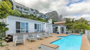A modern building with a swimming pool, lounge chairs, and a view of a mountain. - Ocean Views, Pool, Sleeps 6, Camps Bay - Rontree (Cape Town)