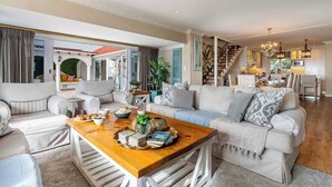 A spacious living area with a wooden coffee table, sofas, and a staircase leading to a kitchen.