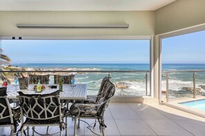 A balcony with a table and chairs overlooking the ocean.