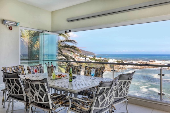 Un balcon avec une table et des chaises, offrant une vue sur la côte.