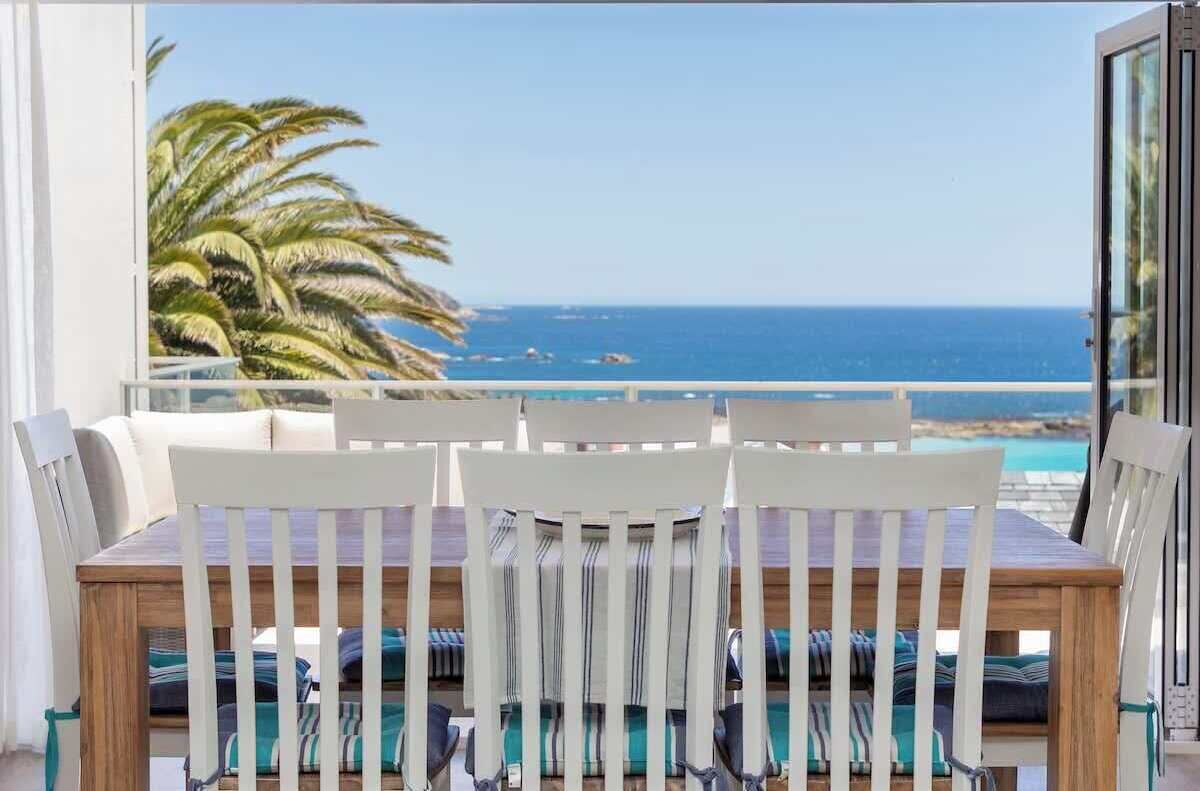 A balcony with a view of the sea and palm trees.