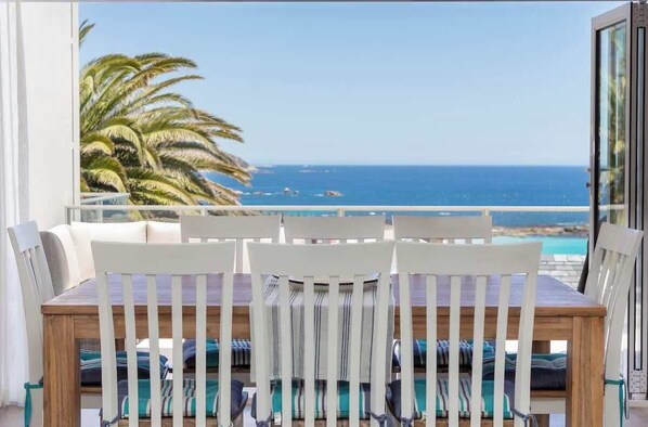 A balcony with a view of the sea and palm trees.