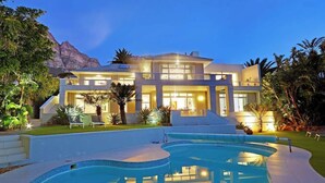 Une maison moderne à deux étages, dotée d’une piscine et offrant une vue sur les montagnes.