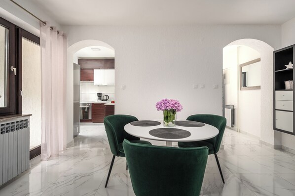 A modern dining area with a round table, green chairs, and a vase of flowers.