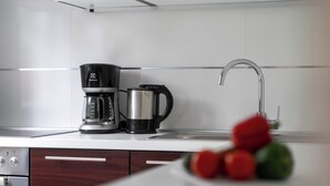 A modern kitchen with a coffee maker, a kettle, and a sink. - Quiet location, 3 persons, air-conditioned, garden with barbecue (Porec)
