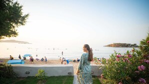 A pathway leading to a beach with people in the water and a distant island.