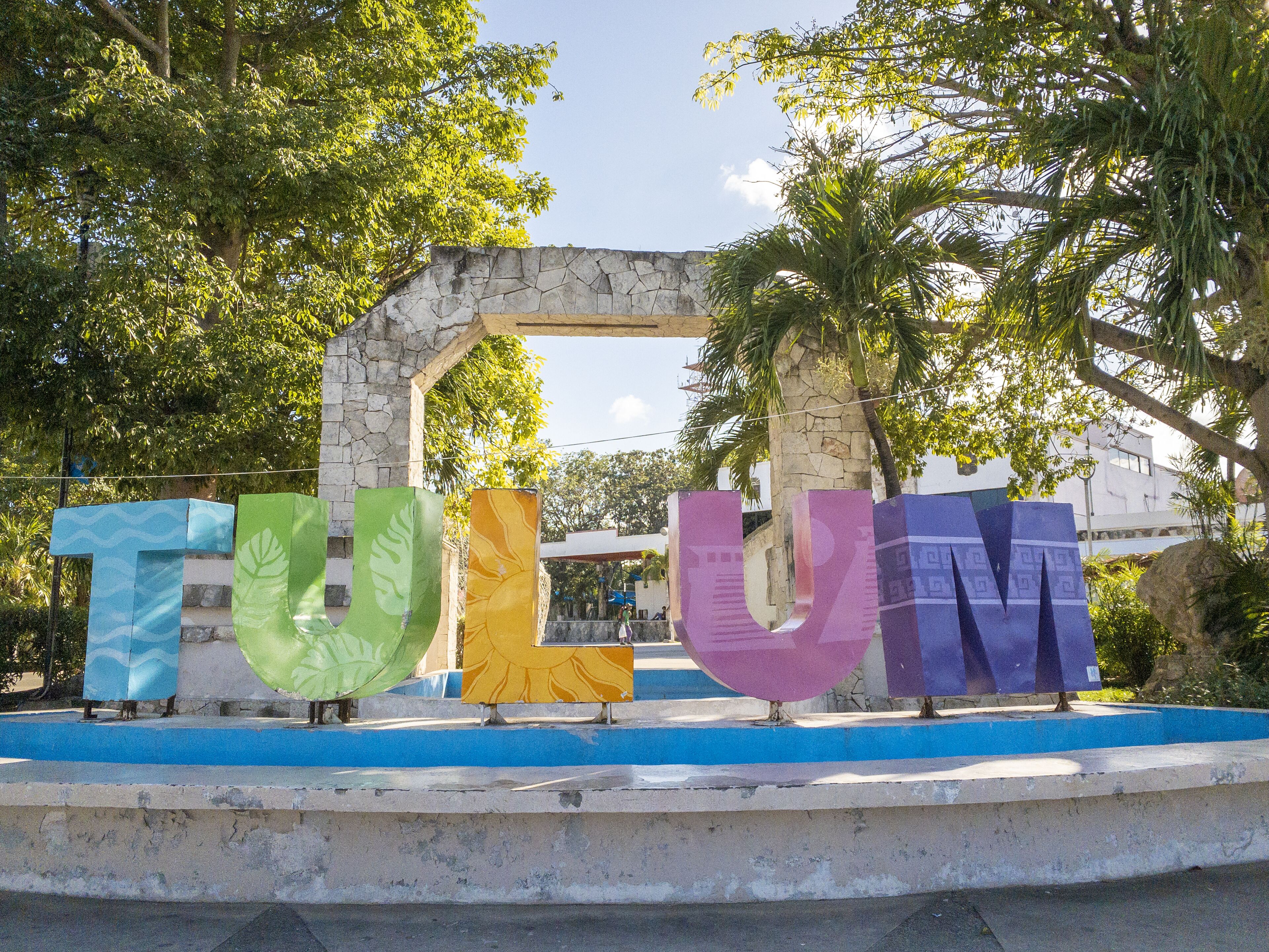 A stone archway with the word "Tulum" in colorful letters.