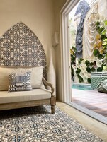 Un coin salon accueillant, agrémenté d’un mur  à motifs, d’un vase décoratif et offrant une vue sur l’espace piscine extérieur.