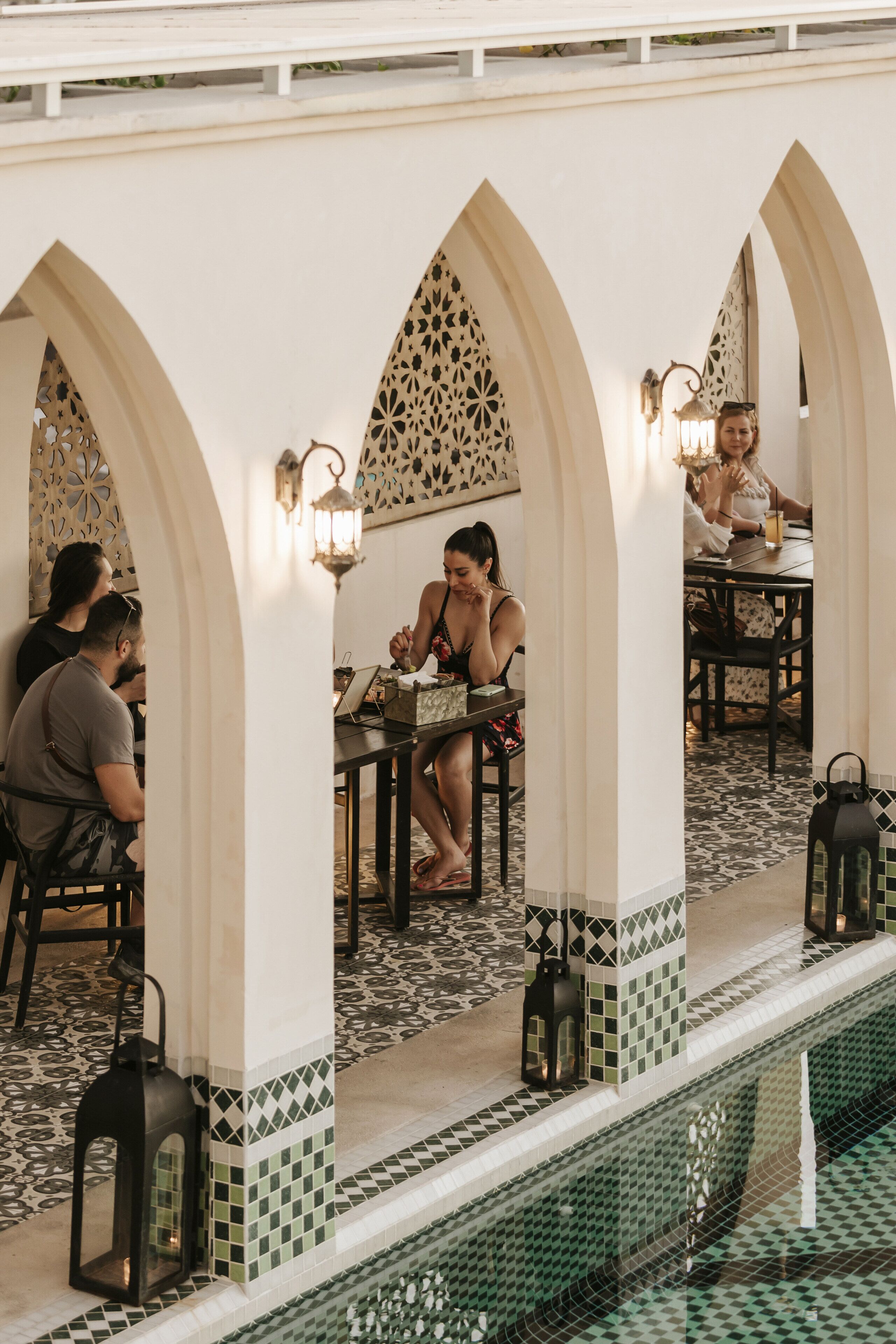 A restaurant with outdoor seating, featuring arches and tiled flooring.