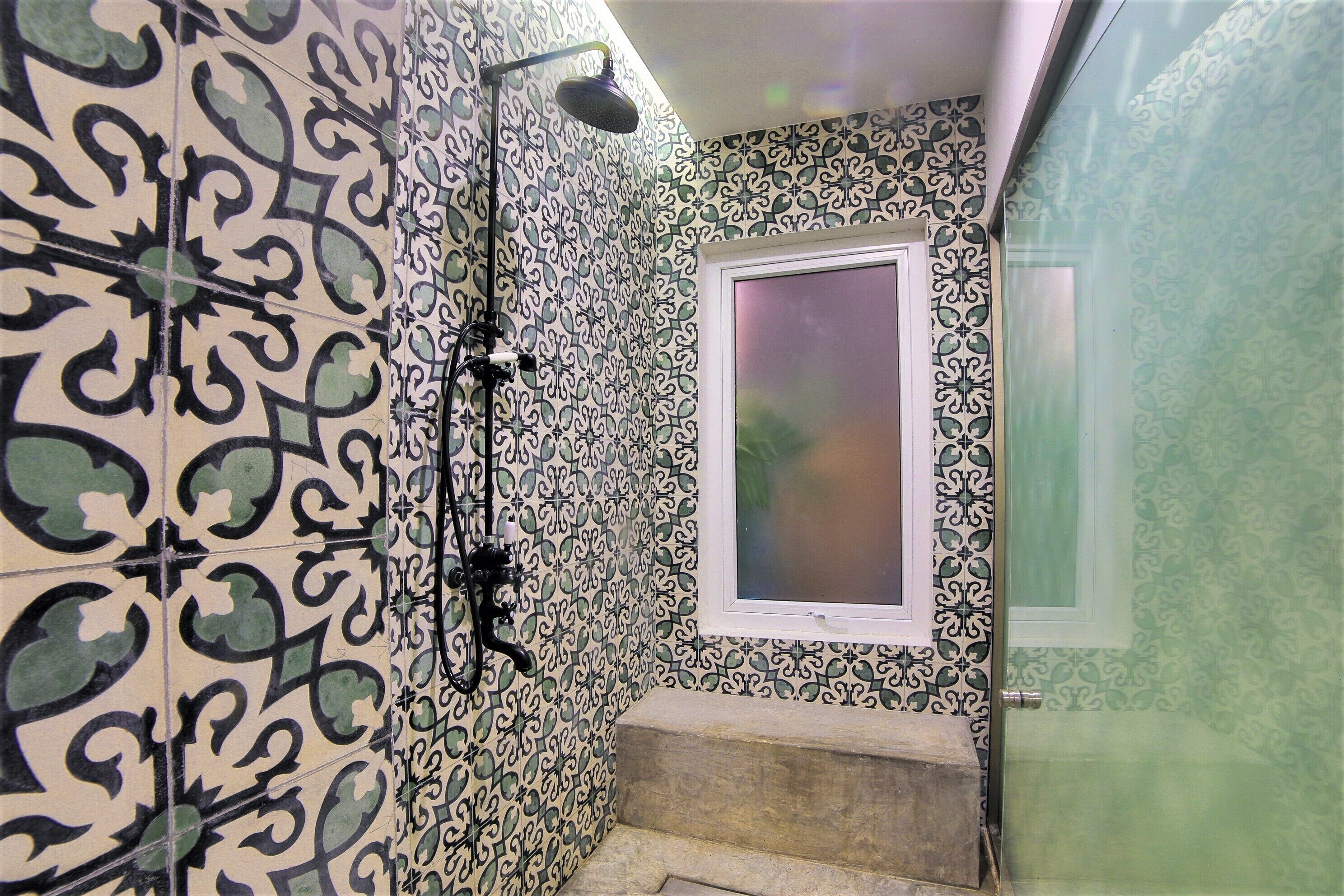 Une salle de bain avec des carreaux décorés, une douche et une fenêtre.