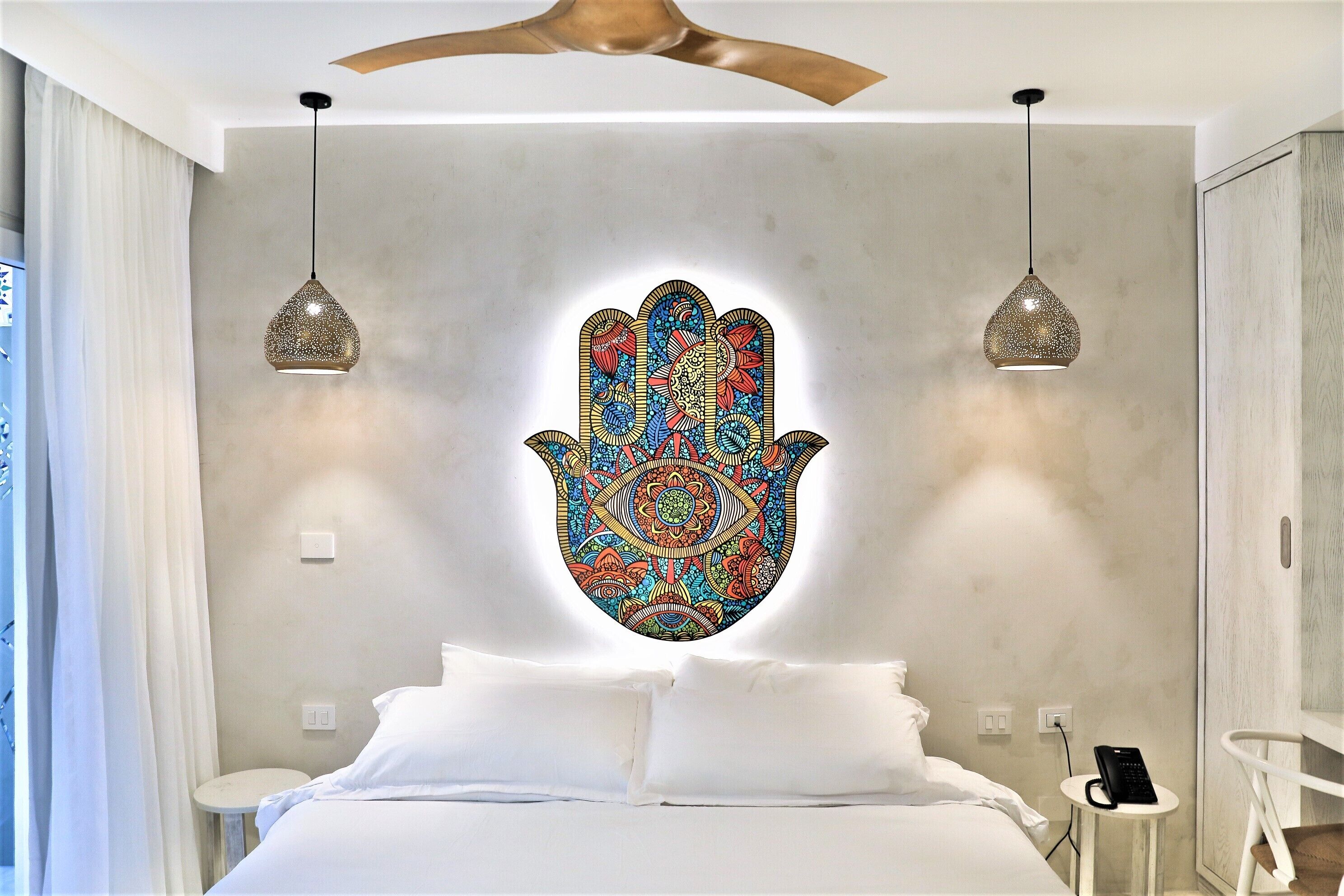 Un dormitorio moderno con una cama grande, un adorno en la pared y dos lámparas colgantes.