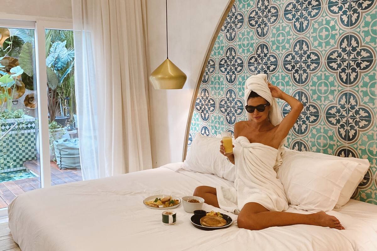 A large bed with white linens, a patterned headboard, and a hanging pendant light.