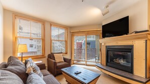 Una sala de estar con sofá, sillón, mesa de centro, chimenea y televisor.