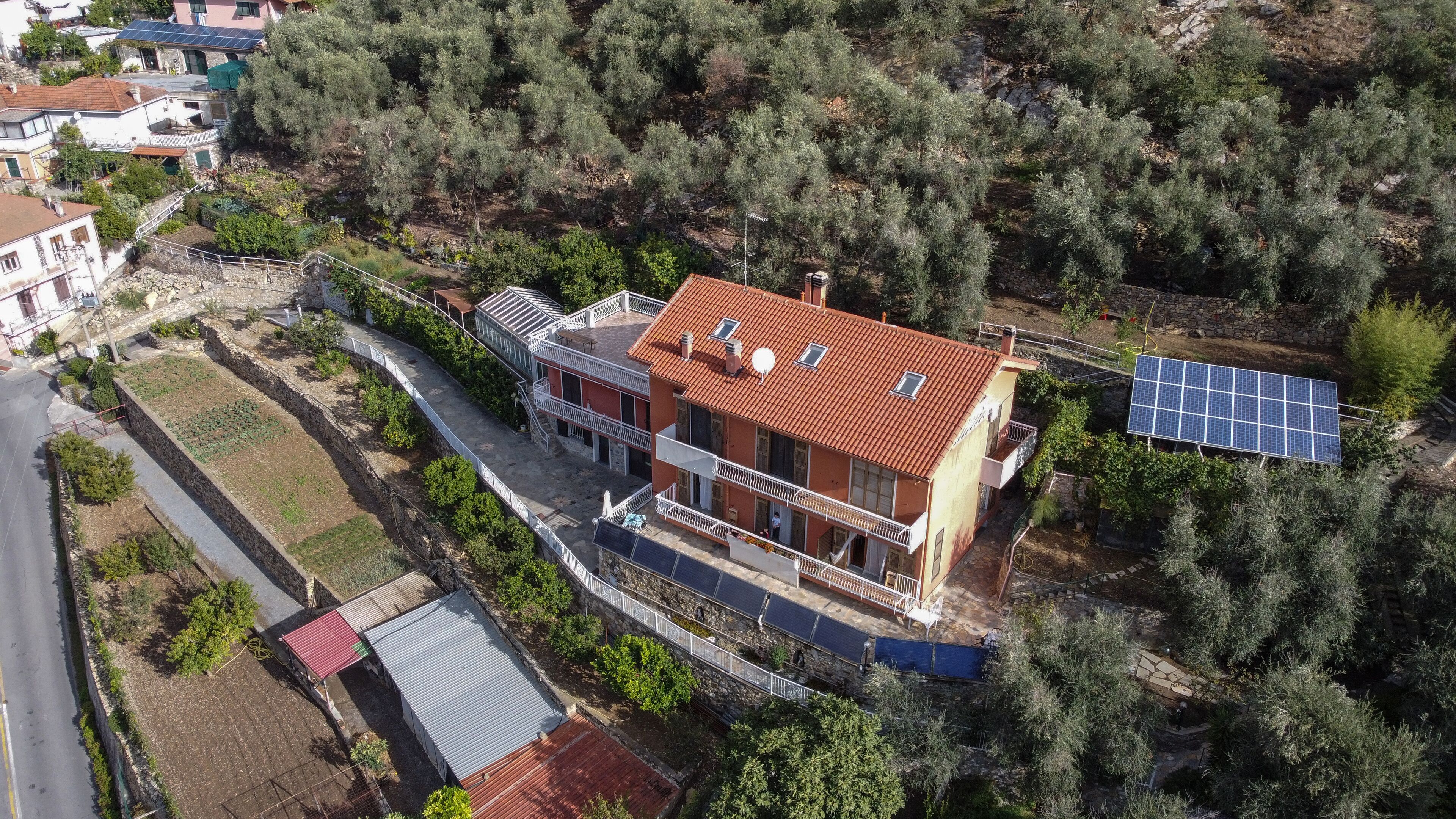 Ein zweistöckiges Haus mit rotem Ziegeldach, Solaranlage und einem Balkon.