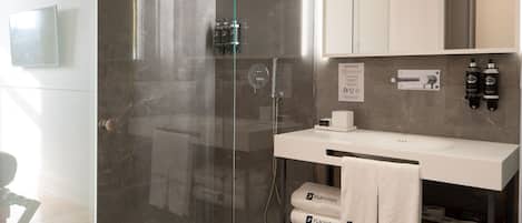A modern bathroom with a glass-enclosed shower, a white vanity with a towel rack, and a large mirror above the sink.