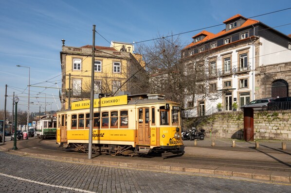 A yellow tram on a cobblestone street with buildings in the background. - Memoria Porto FLH Hotels (Porto)