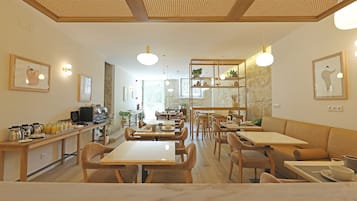 Un café amplio con mesas y sillas de madera, una barra con equipo para preparar café y obras de arte enmarcadas en las paredes.