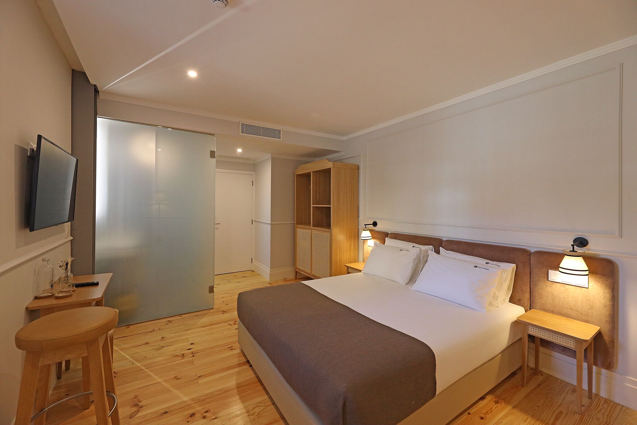 A hotel room with a bed, a TV, a desk, and a wardrobe.